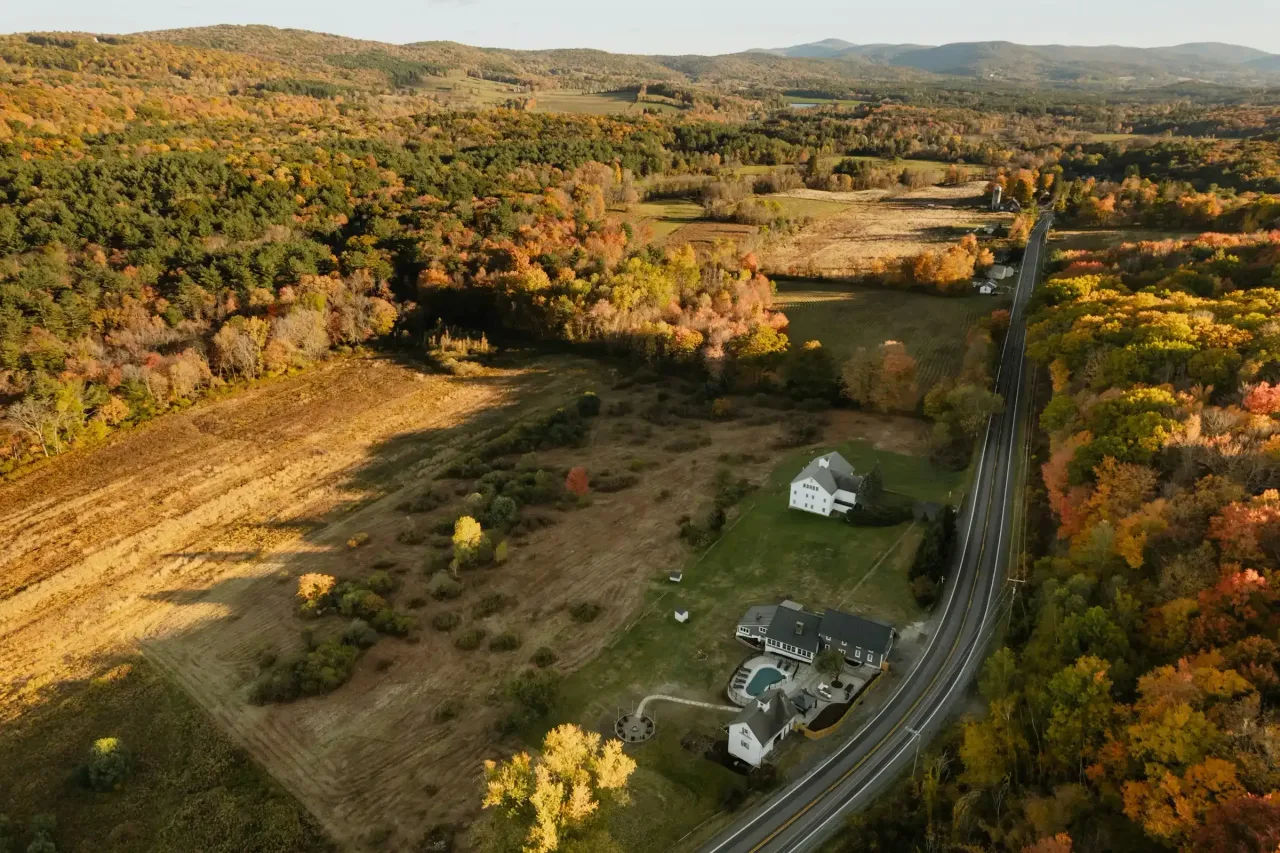 Aerial view of open land and autumn woods