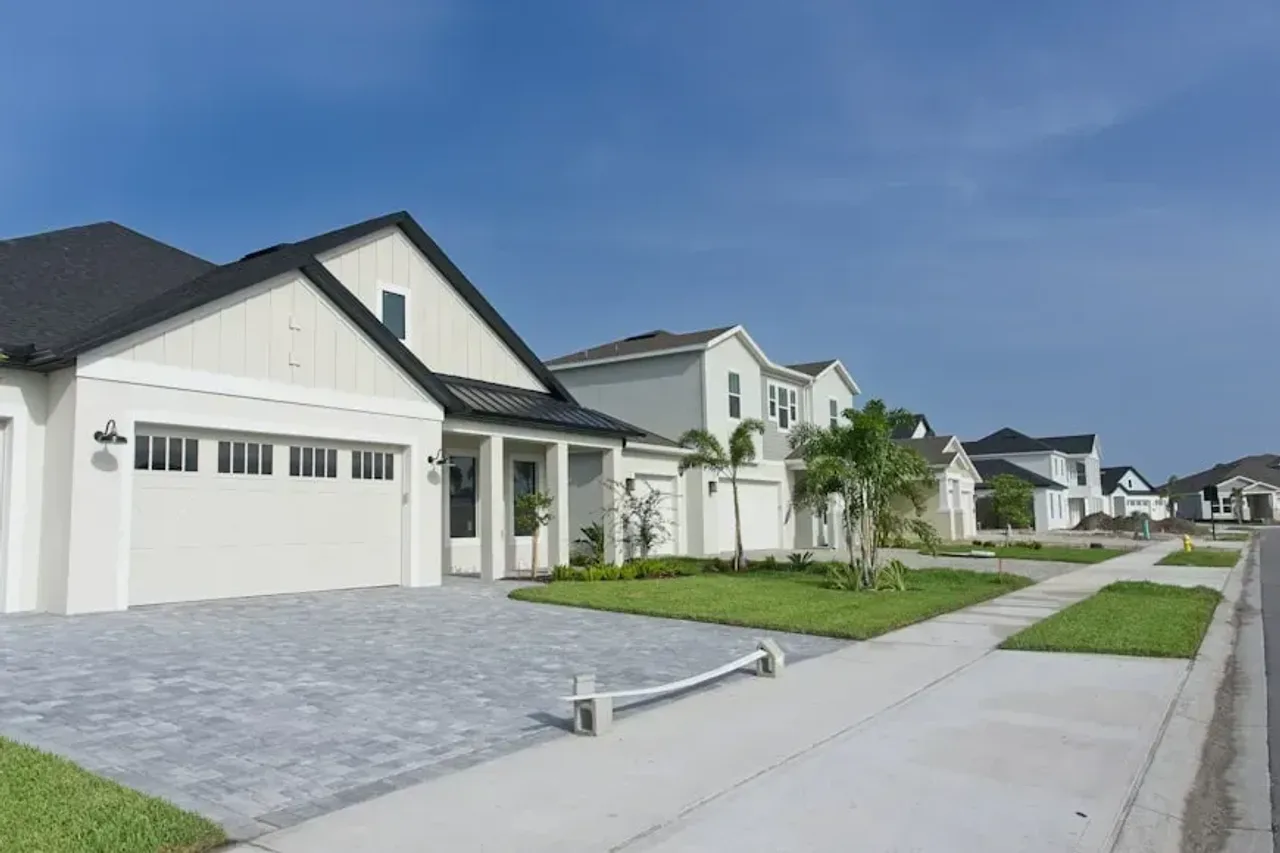 White single-story home with a paver driveway and palm trees